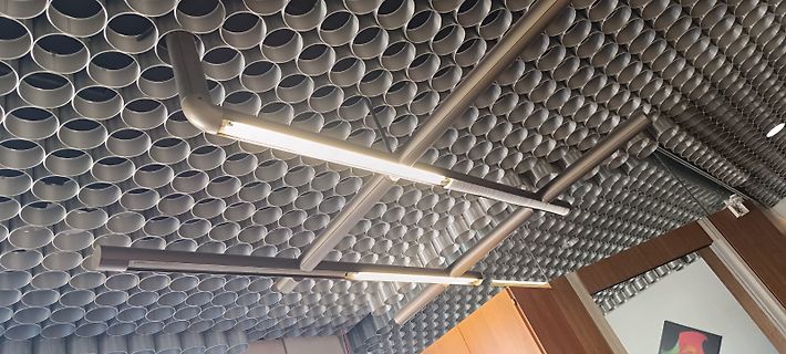 Deckenbeleuchtung vor einer Wand aus Rohren