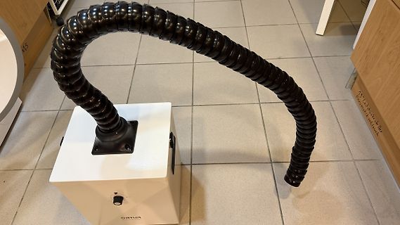Absaugarm an einem weißen Gehäuse