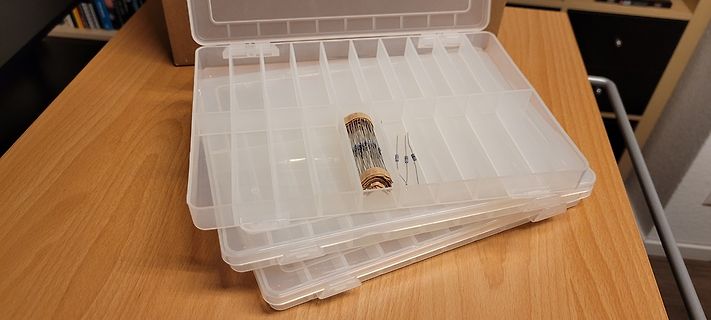 Transparente Kunststoffbox mit Kleinteilen auf Holztisch