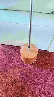 Metallstange auf braunem Teppich vor weißem Sofa
