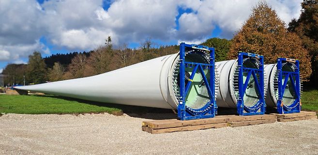 Drei Windkraftanlagen-Rotorblätter auf Transportgestellen