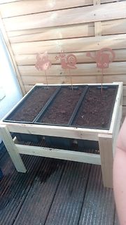 Hochbeet mit Pflanzgefäßen und Gartendekoration