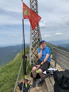 Mann auf Berggipfel mit Flagge und Wanderstock