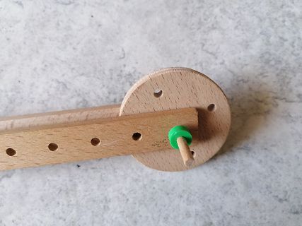Holzbauteil mit Lochreihe und grünem Stift