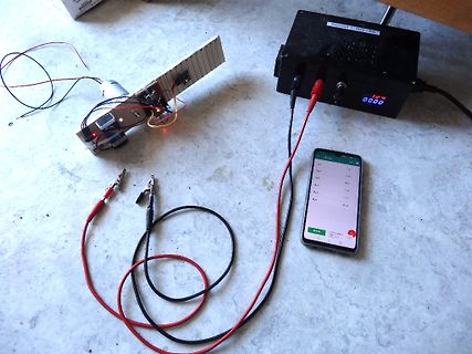 Elektronik-Aufbau mit Netzteil, Smartphone und Messkabeln