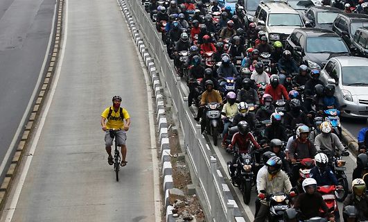 Radfahrer auf einer Straße neben dichtem Verkehr