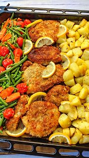 Gebratenes Fleisch mit Kartoffeln, Bohnen und Zitronenscheiben auf Backblech