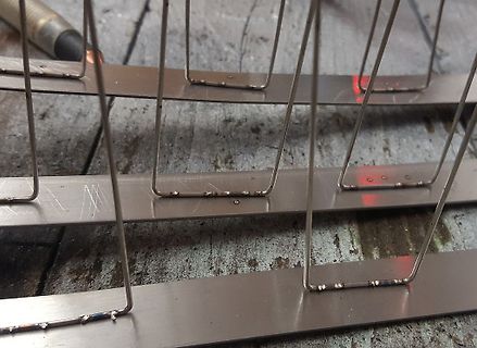 Metallstreifen mit Drahtbügeln auf Holzuntergrund