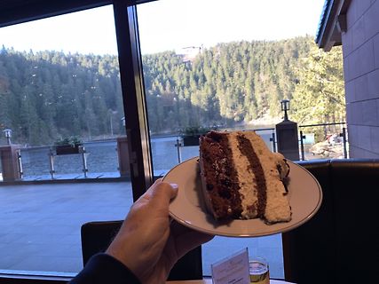 Stück Schokoladenkuchen auf einem Teller vor Seeufer