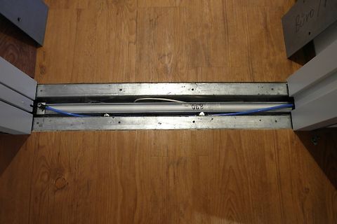 Metallprofil mit Kabel und Beschriftung auf Holzboden