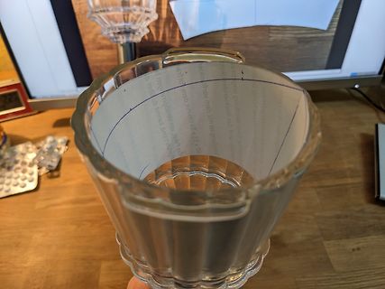 Glasbecher auf Holztisch vor Monitor