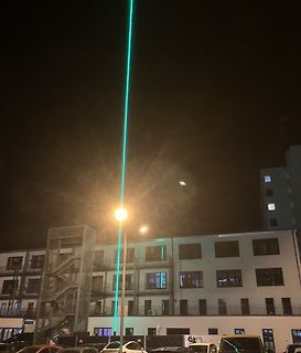 Grüner Laserstrahl in der Nacht über einem Gebäude