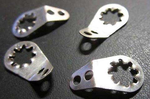 Vier metallische Halterungen mit sternförmigen Ausschnitten